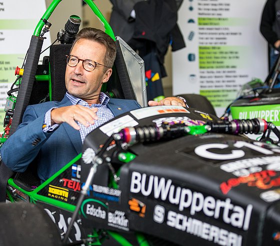 Der Rektor der Bergischen Uni testet einen Rennwagen des Green Lion Racing Teams der Uni.