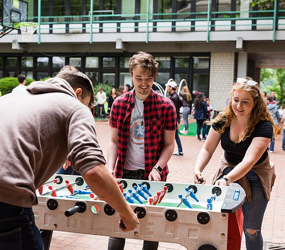 Studierende spielen Tischkicker im Bibliotheksinnenhof