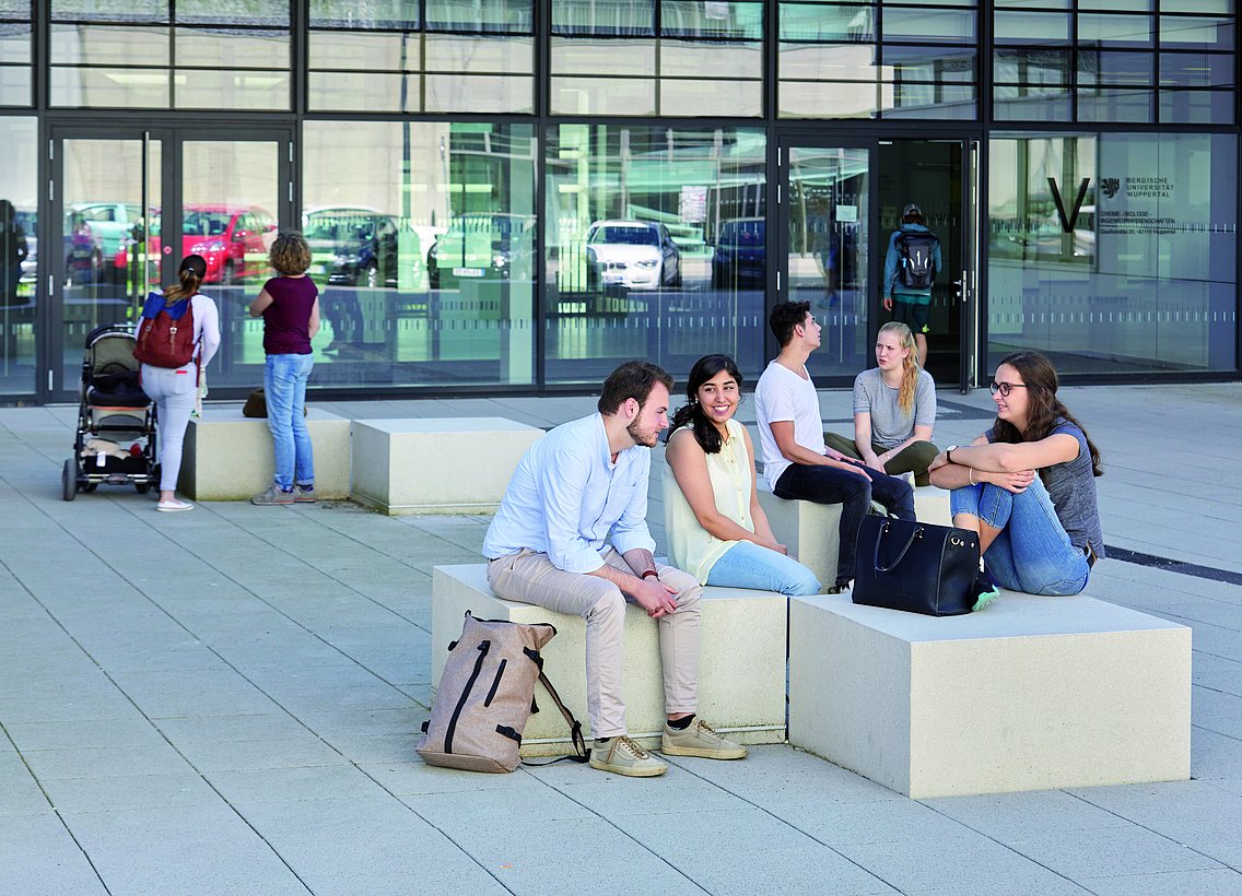 Studierende sitzen vor dem Gebäude VW am Campus Grifflenberg