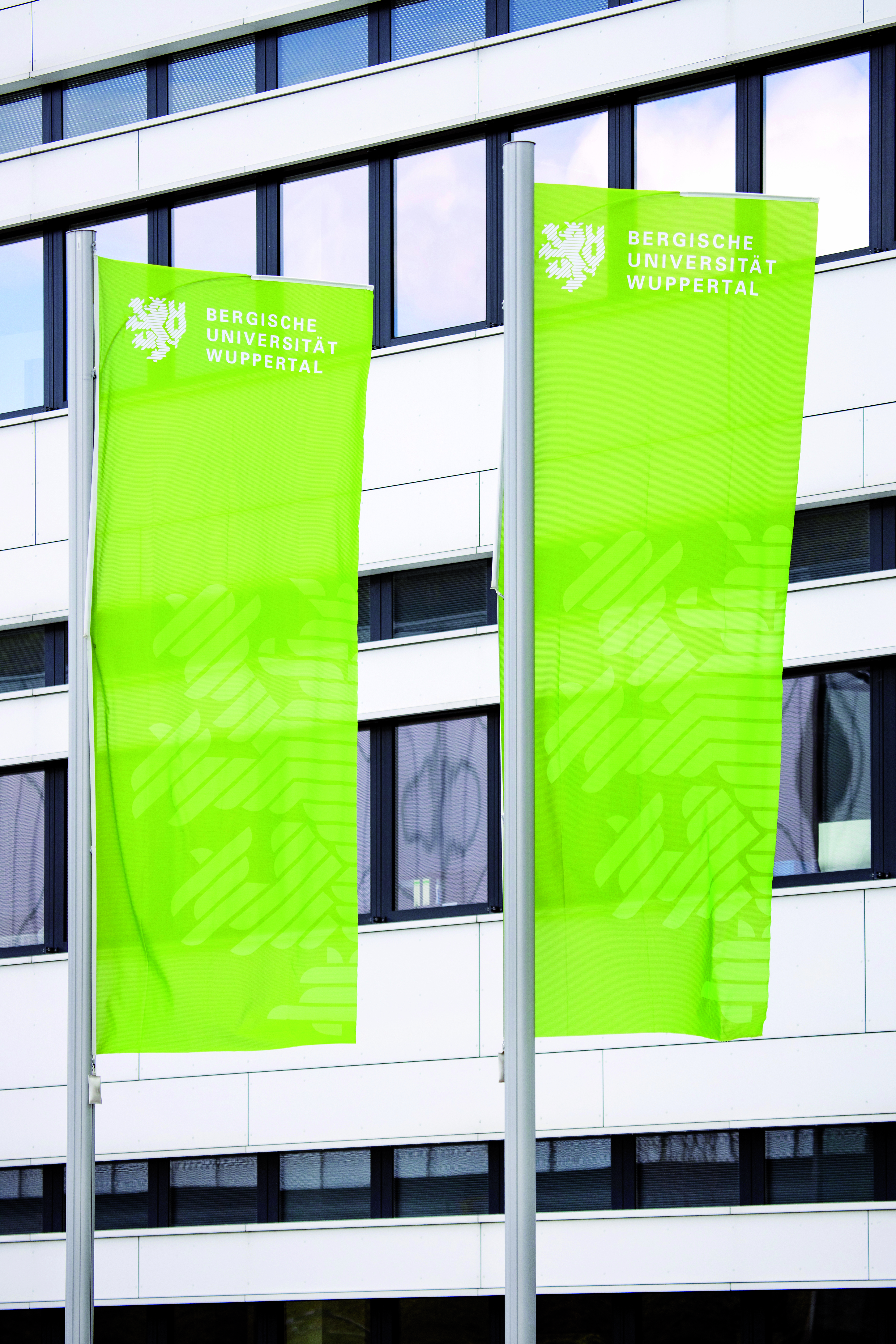 grüne Uni-Flaggen vor Gebäude VW