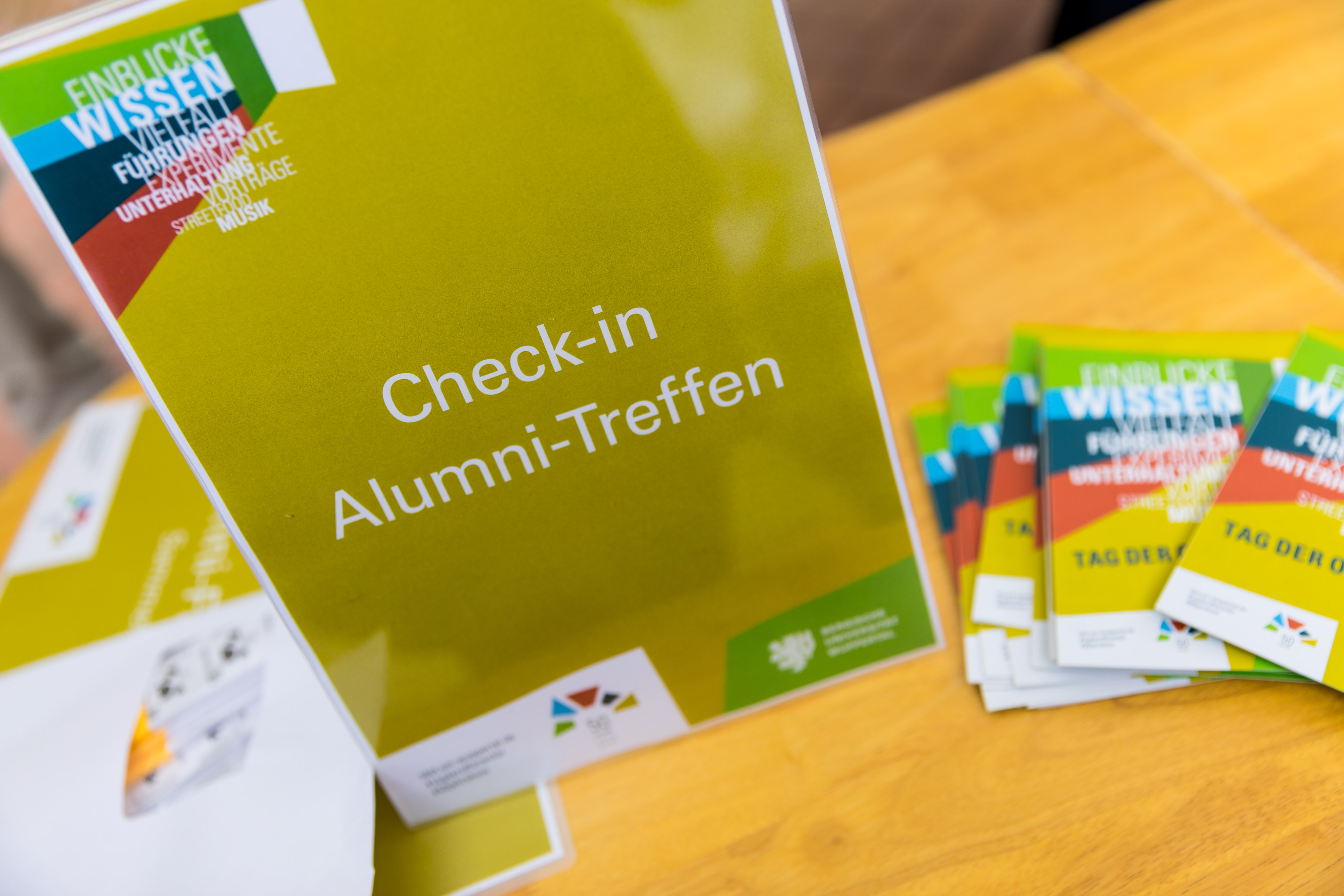 Schild mit Aufschrift Check in Alumni-Treffen
